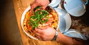 pizza som pizzabakeren legger litt ruccola på
