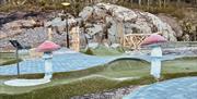 Minigolfbanen på Topcamp Sjøsanden, med to fluesopper som pynt på siden, kunstgress og brostein