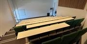 Vitenamfiet i Arendal fotografert fra bakerste rad med 7 stolrader nedover mot fremvisningsvegg.