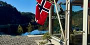 Fasade Øygarden Gård, med flagg i flaggstanga og utsikt ut til vannet