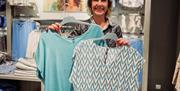 Smilende ansatt hos klesbutikken Zavanna, viser frem to bluser