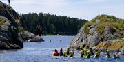 gruppe med mennesker i vannet med hjelm og våtdrakt klare for litt coasteering