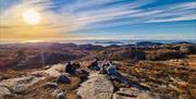 En gjeng som sitter på fjellet, med utsikt ut over havet