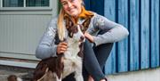 ung kvinne sittende foran en av Hillestad feriesenters hytter med en hund.