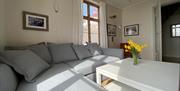 Utsikt fra stua inne i leiligheten. Grå sovesofa som kan bli til seng til 2