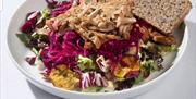 Bilde av fargerik salat med kylling på toppen, og to skiver på kanten