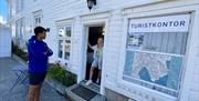 En mann og en dame står utenfor Lillesand Turistkontor.