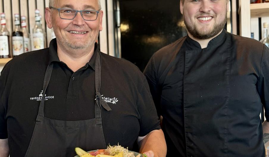 To smilende kokker som viser stolt fram en kyllingsalat To smilende kokker som viser stolt fram en kyllingsalat